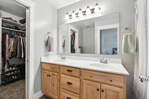 Full bath featuring a spacious closet and double vanity