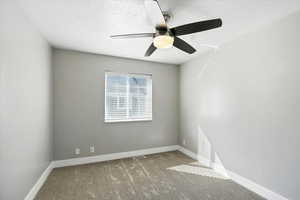 Carpeted spare room featuring a textured ceiling and ceiling fan