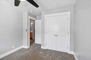 Unfurnished bedroom featuring dark carpet, a closet, ceiling fan, and a textured ceiling