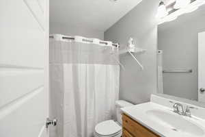 Full bathroom with vanity, a textured ceiling, and a shower with curtain