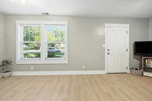 Unfurnished living room featuring light wood-style flooring and a textured ceiling