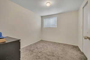 Carpeted spare room featuring baseboards