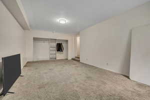 Unfurnished living room featuring light colored carpet and stairs