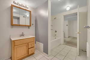 Bathroom with shower / bathtub combination, vanity, and light tile patterned flooring