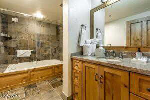 Full bath featuring vanity,  shower combination, and light stone finish flooring