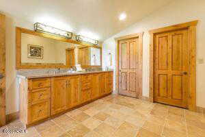 Full bath with double vanity, lofted ceiling, and recessed lighting