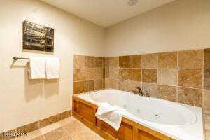 Full bathroom featuring a jetted tub and light tile patterned flooring