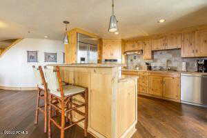 Kitchen with a kitchen bar, light countertops, dark wood-style floors, hanging light fixtures, and recessed lighting