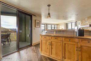 Kitchen with dark wood-type flooring, pendant lighting, brown cabinetry, and light countertops