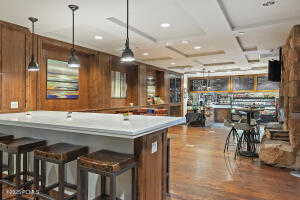 Kitchen with hanging light fixtures, wood finished floors, light countertops, brown cabinets, and wood walls