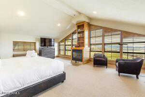 Bedroom featuring light carpet and a fireplace