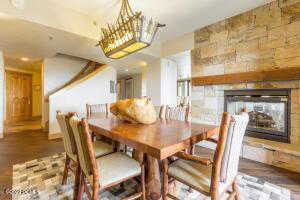 Dining space with wood finished floors, a stone fireplace, and a chandelier