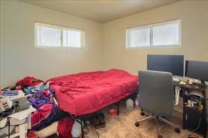 Carpeted bedroom featuring multiple windows and an office area