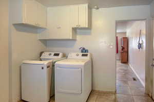 Laundry room with light tile patterned flooring, washing machine and dryer, and cabinet space