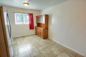 Unfurnished dining area featuring baseboards and light tile patterned floors