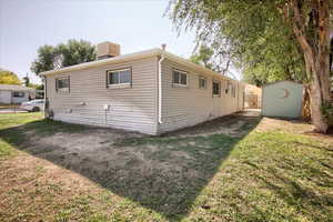 View of side of property featuring a shed, a lawn, and a chimney