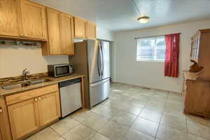 Kitchen with stainless steel appliances, light tile patterned floors, and dark stone counters