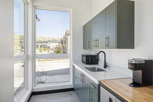 Kitchen with gray cabinetry, black microwave, a residential view, and concrete floors