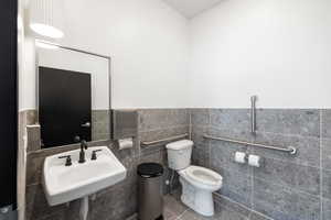 Half bathroom with tile walls, a wainscoted wall, and tile patterned floors