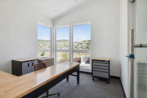 Office featuring dark colored carpet and lofted ceiling