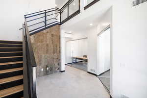 Stairs with concrete flooring, a towering ceiling, and recessed lighting