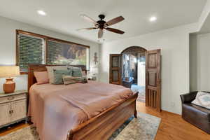 Primary Bedroom with light wood finished floors, recessed lighting, a ceiling fan, and arched walkways