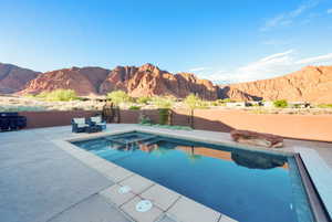 View of pool featuring a mountain view, a pool with connected hot tub, a fenced backyard, and a patio
