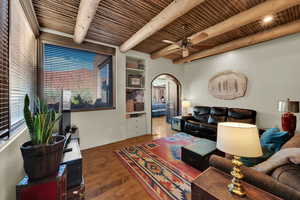 Second Living room with arched walkways, ceiling fan, wood finished floors, and a wood ceiling with exposed beams