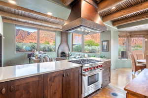 Kitchen featuring premium stove, a wooden ceiling with exposed beams, island exhaust hood, light stone counters, and light wood-type flooring