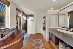 Primary Bathroom featuring vanity, a stall shower, a freestanding tub, wood finished floors, and backsplash