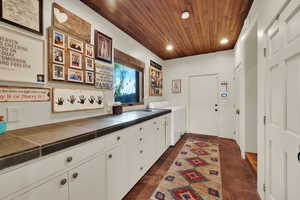 Laundry room with cabinet space, wood ceiling, washing machine and clothes dryer, and recessed lighting