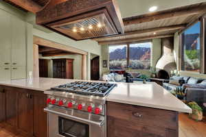 Kitchen with open floor plan, luxury stove, dark brown cabinets, range hood, and light wood finished floors