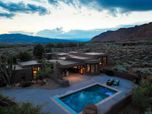 Back of property featuring an in-ground hot tub, a patio area, a mountain view, stucco siding, and an outdoor pool