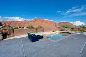 View of swimming pool featuring a mountain view, a fenced backyard, a patio area, and a diving board