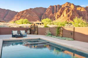 View of swimming pool with a gate, a pool with connected hot tub, a mountain view, and a patio