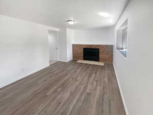 Unfurnished living room with a fireplace, a textured ceiling, and dark wood-style floors