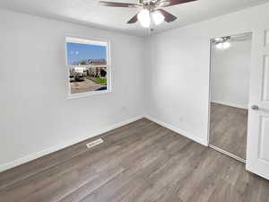 Unfurnished bedroom featuring wood finished floors, ceiling fan, and a textured ceiling