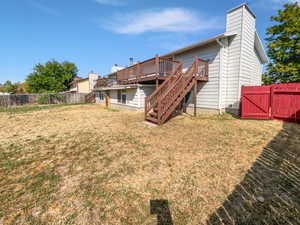 Back of house with a fenced backyard, stairway, a chimney, a deck, and a gate