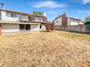 Rear view of house featuring stairway, a deck, a fenced backyard, and a chimney