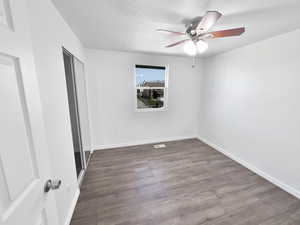 Unfurnished bedroom featuring wood finished floors, ceiling fan, a closet, and a textured ceiling