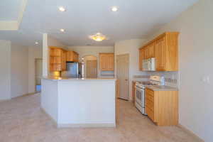 Kitchen with white appliances, backsplash, open shelves, light brown cabinetry, and recessed lighting