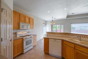 Kitchen with tasteful backsplash, white appliances, hanging light fixtures, light tile patterned flooring, and recessed lighting