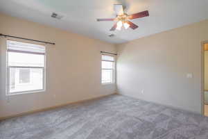 Carpeted spare room with ceiling fan and baseboards