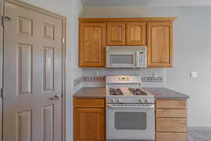 Kitchen with white appliances, backsplash, and dark stone counters