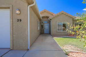 Doorway to property featuring stucco siding, a garage, and a yard