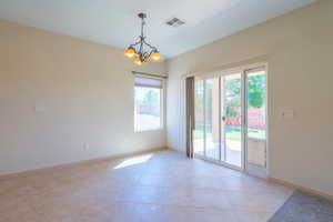 Empty room with a chandelier and light tile patterned floors