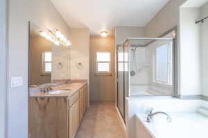 Bathroom with healthy amount of natural light, double vanity, a shower stall, and a bath