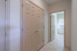 Corridor with light tile patterned flooring and baseboards