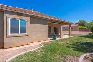 Rear view of property featuring a patio area, stucco siding, and a lawn