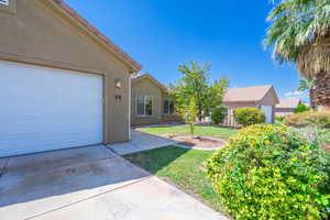 View of front facade with stucco siding, a garage, a front yard, and driveway